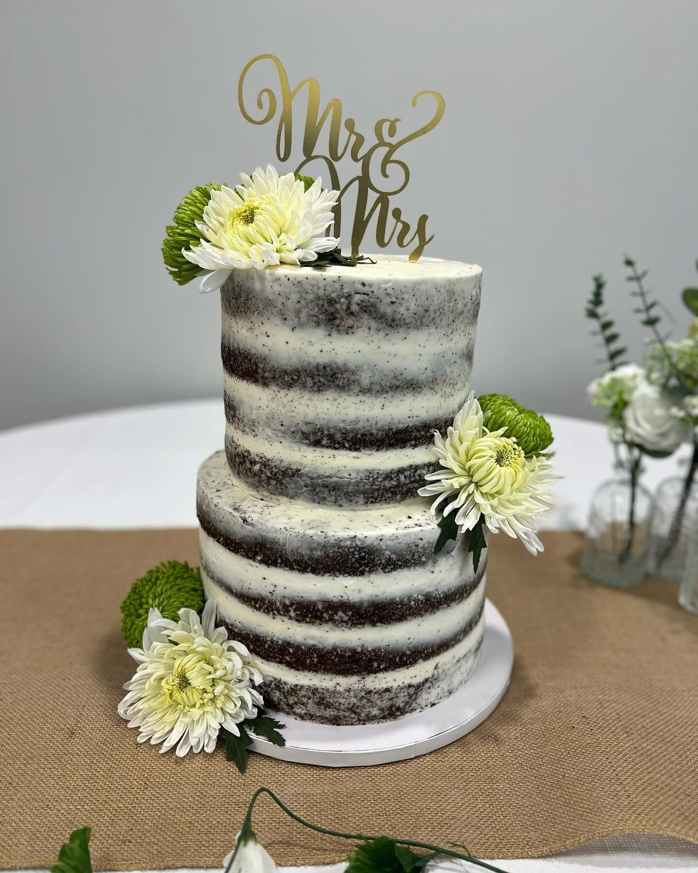 Two-tier semi-naked wedding cake with white and green florals